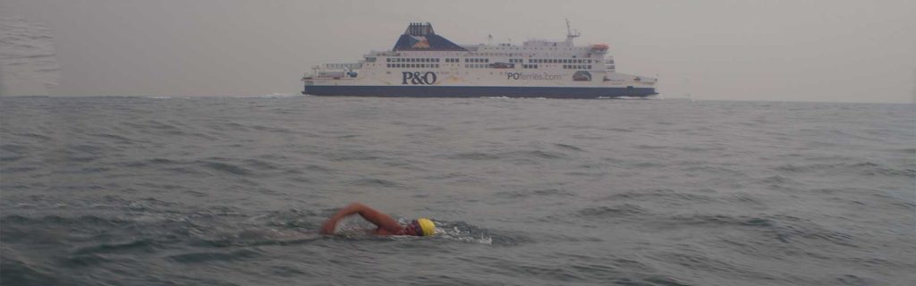 A person swimming in the water near a ferry.