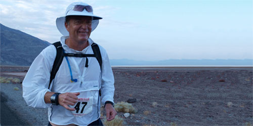 A man in white shirt and hat standing on beach.