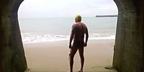 A man standing on the beach with his back to the water.