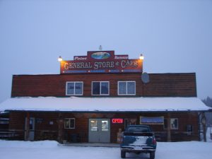 A car parked in front of a store with snow on the ground.