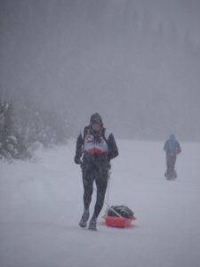 A man walking in the snow with a sled.