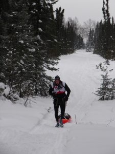 A person on skis in the snow near trees.