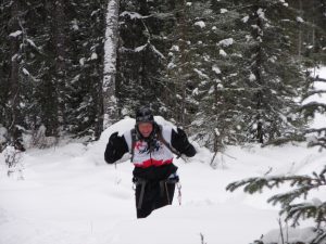 A man is skiing in the snow near trees.