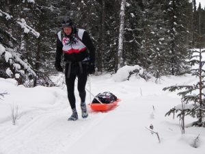 A man is skiing in the snow with his sled.