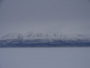 A large body of water with snow covered mountains in the background.