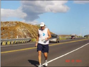 A man is walking on the side of a road.