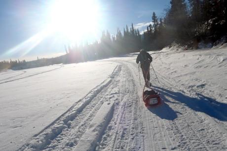 A person is pulling a sled down the snow.