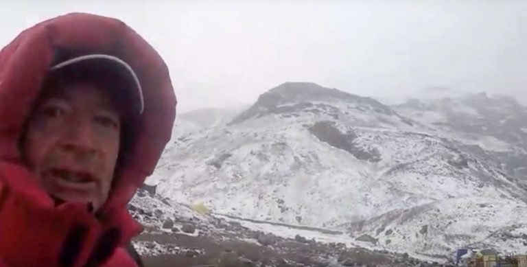 A person holding onto a camera while standing in the snow.